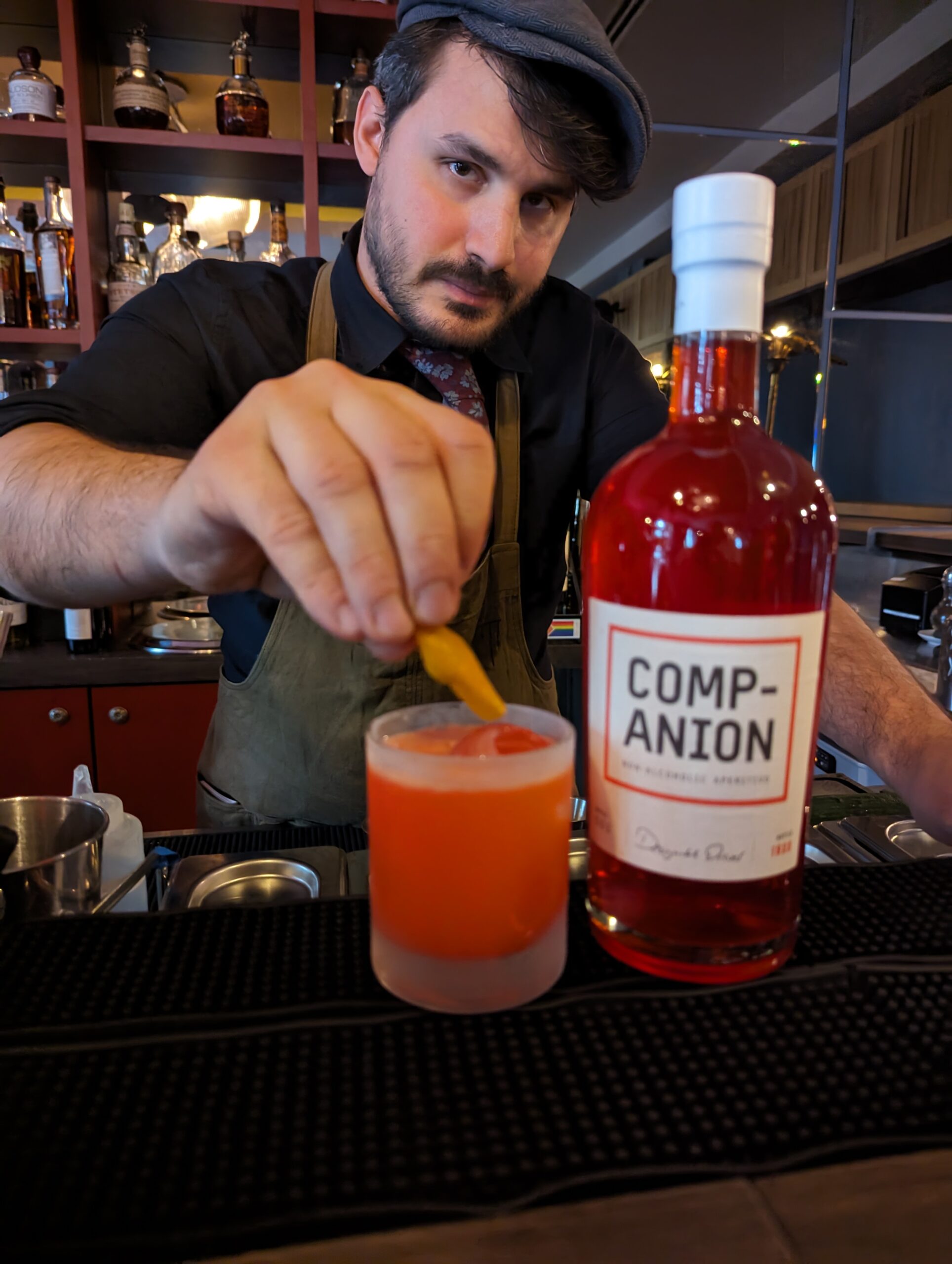 A barkeep adding an orange slice to a drink mixed with the Companion aperitivo.